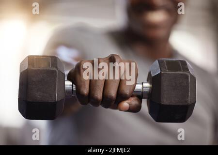 Closeup of unknown african american athlete lifting dumbbell during arm workout in gym. Strong, fit, active black man training with weight in health Stock Photo