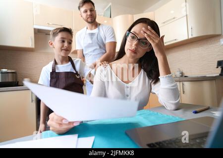 Bothered female looking through documents with family members behind her Stock Photo