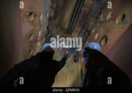 Drone male inspection operated by construction worker on furnace in confined site Stock Photo