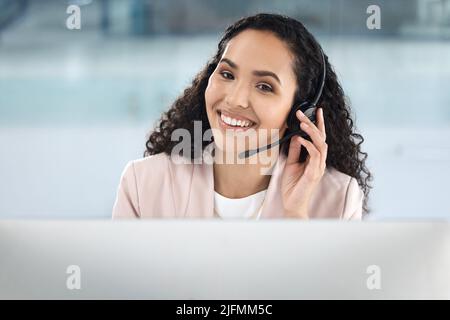 Businesswoman working in a customer service call center. Happy IT support agent. Customer service assistant making a call on her headset. Sales rep Stock Photo