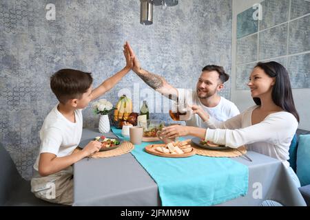 Father and son giving each other high five during dinner Stock Photo
