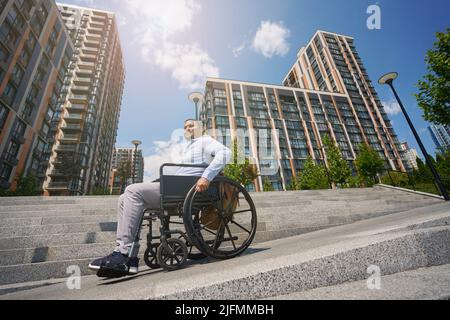 Young man seated in wheel chair going down stairs Stock Photo