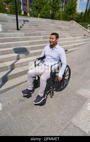 Disabled man going down stairs in wheel chair Stock Photo