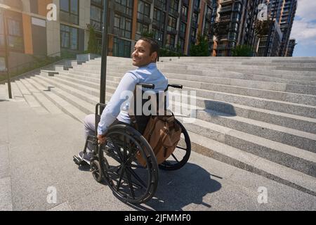 Pleased disabled person seated in manual wheel chair outdoors Stock Photo