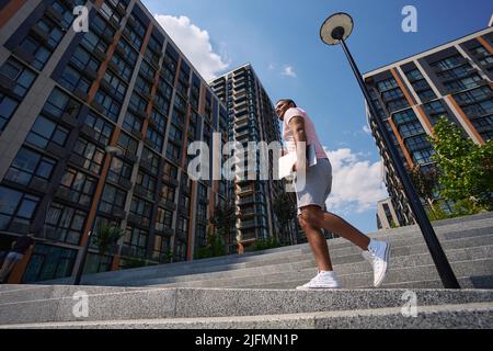 Male person with laptop going up stairs Stock Photo