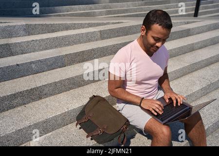 Serious young man working on his laptop outdoors Stock Photo