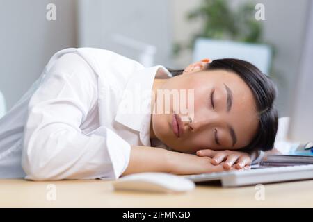 Woman office worker tired Asian sleeps on the desk, overtired sleeps in the day. Stock Photo