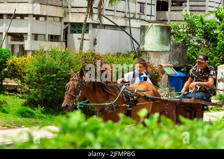 Photo of an elderly man, a child and a girl, these last two are wearing uniforms for elementary school in Cuba, they are traveling on top of a handmad Stock Photo