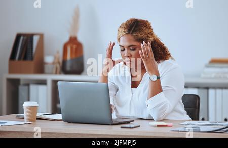 Stressed African American businesswoman making a mistake while using her laptop in the office. Professional black woman feeling pressured while using Stock Photo