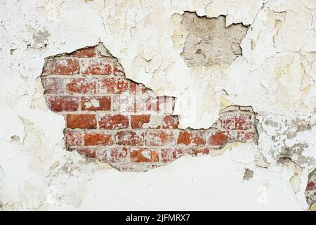 Texture of an old brick wall with damaged plaster and cracked paint. Stock Photo