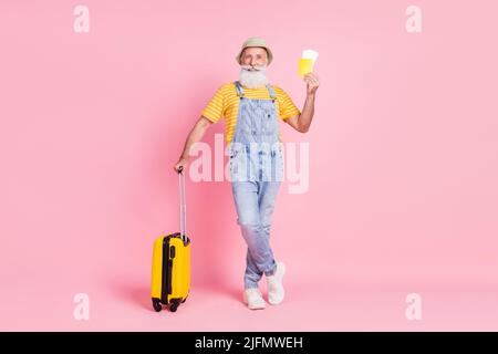 Full length body size view of attractive retired cheerful man holding bag pass fly isolated over pink pastel color background Stock Photo
