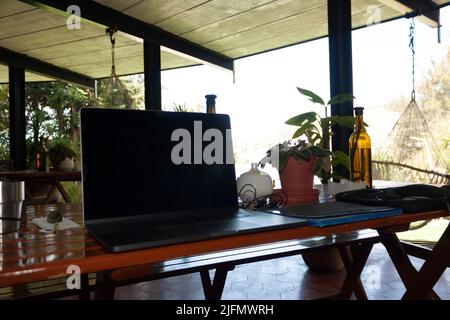 Outdoor workspace with wireless technology, internet connection and basic equipment: computer, cell phone, home office headset in outdoor garden Stock Photo