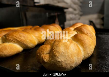 Close-up of a bun or bakery product in the form of a pigtail on a baking sheet from the oven. Fresh pastries Stock Photo