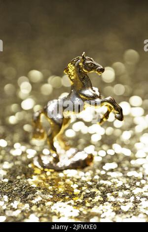 A gold horse figurine on a sparkling gold background. Stock Photo
