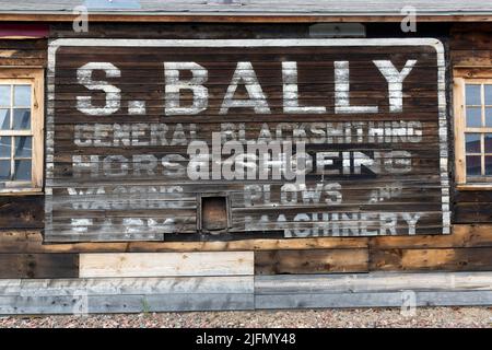 An old and faded historic 1911 sign on the side of the Sam Bally blacksmith shop in Grand Marais, Minnesota Stock Photo