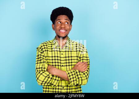 Photo of young brunette nice guy crossed hands look empty space wear yellow shirt isolated on blue color background Stock Photo
