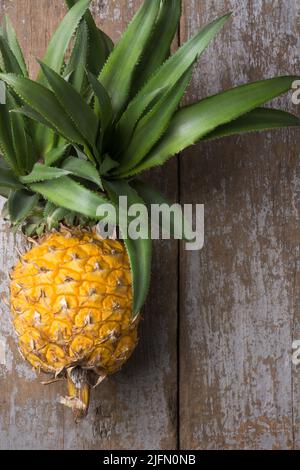 fresh whole ripe pineapple, placed on a wooden table top, taken from above with copy space Stock Photo