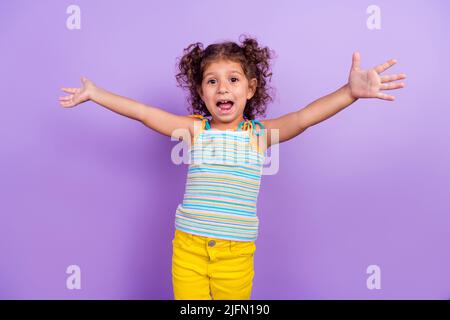 Photo of impressed little brunette girl want hug wear striped top isolated on violet color background Stock Photo