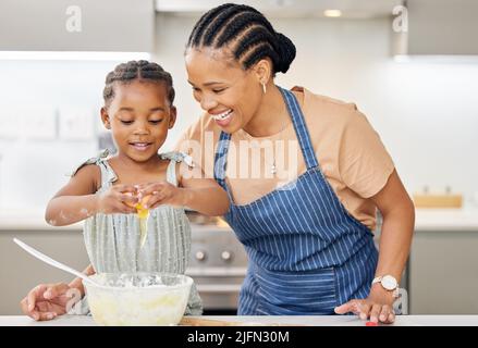 There you go. Shot of an attractive young mother bonding with her daughter and helping her bake in the kitchen at home. Stock Photo