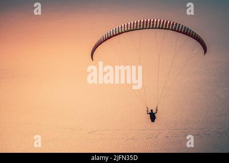 Paragliding in the sky at sunset. Paraglider flying over the Oludeniz Beach. Babadag, Fethiye, Turkey Stock Photo