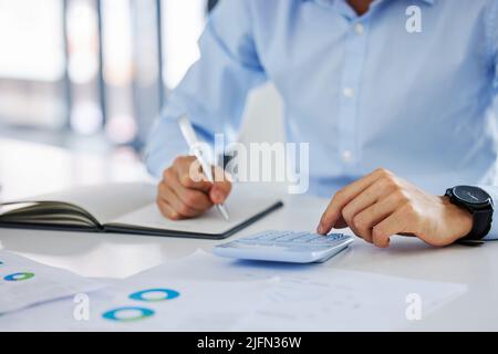 Closeup of an unknown businessman using his calculator while working on paperwork. Closeup of an unknown businessman using his calculator while Stock Photo