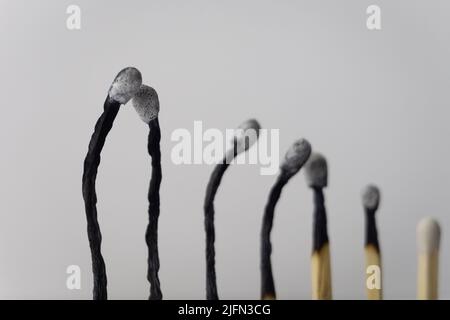 Burnt and bent matchsticks. Wooden matchsticks burning in sequence on a gray background. Selective Focus. Stock Photo