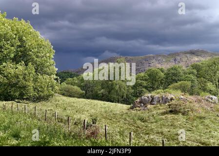 Dark storm clouds gathering over Muncaster Fell on a sunny summers day, Lake Distract  Eskdale Cumbria England UK Stock Photo