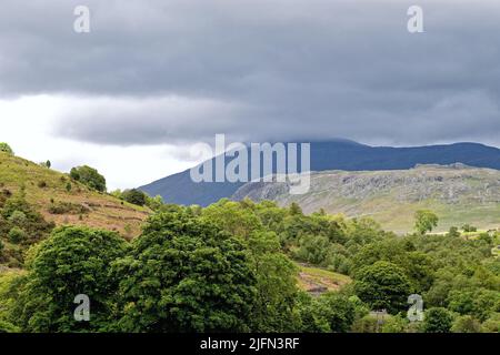 The Scafell range of mountains in storm clouds dominating the skyline in Boot, Eskdale on a summers day Lake District Cumbria England UK Stock Photo