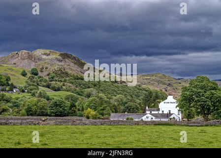 The Brook House Inn nestled amongst dramatic fells with dark storm clouds gathering, Eskdale Lake District Cumbria England UK Stock Photo