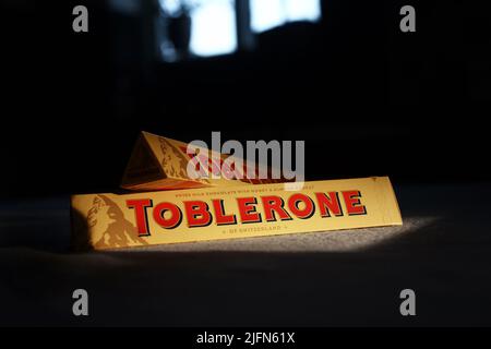 A Toblerone chocolate bar in the evening sun on a kitchen table in home. Toblerone is to lose the "of Switzerland" label from the front of its packaging after a decision to open a production site for the chocolate in Slovakia. Stock Photo
