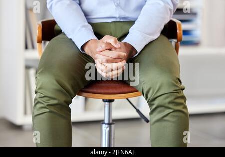 Businessman with his hands clasped showing power and confidence. Unknown mixed race professional sitting alone in an office and patiently waiting Stock Photo