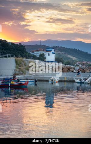 Seascape scenery of fishing boats in a harbor and a little chapel in the background Stock Photo