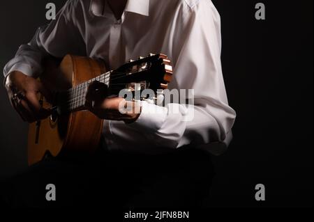 Spanish classical guitar and guitarist's hands up close on a black background with copy space Stock Photo