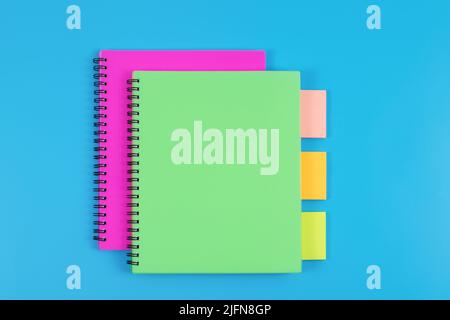 Colourful notebooks and sticky notes arranged on blue background, top view. Stock Photo