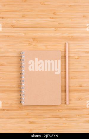 Eco friendly closed blank spiral notepad and pencil on wooden table, top view. Stock Photo
