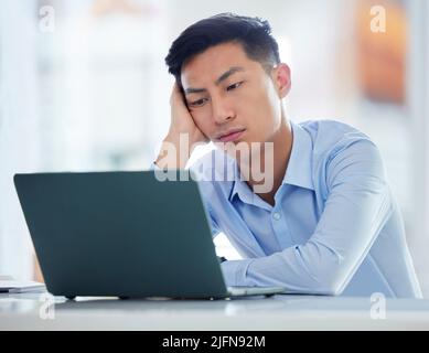 One young asian business man looking bored, tired and demotivated while waiting on slow laptop connection error. Lazy man slacking and ignoring Stock Photo