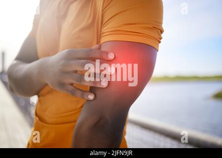 A man with arm pain. A sporty and active African American man is touching his sore arm. A man with arm pain. A sporty and active African American man Stock Photo