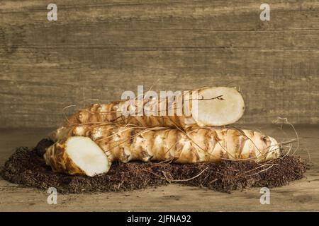 Sweet crispy Jerusalem artichoke tuber cut into pieces, with hummus on a wooden background. Stock Photo