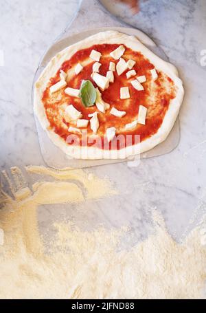 background photo of some pizzas on marble top with flour and traditional italian ingredients ,traditional Neapolitan pizza Stock Photo