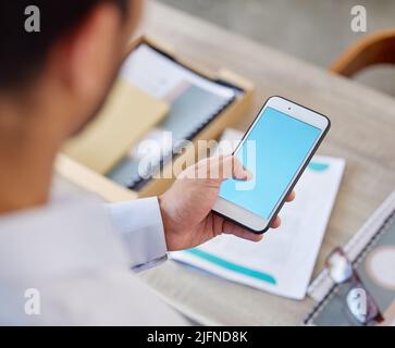 Unknown businessman browsing the internet on a cellphone in an office. Mixed race professional standing alone and scrolling through schedule and Stock Photo