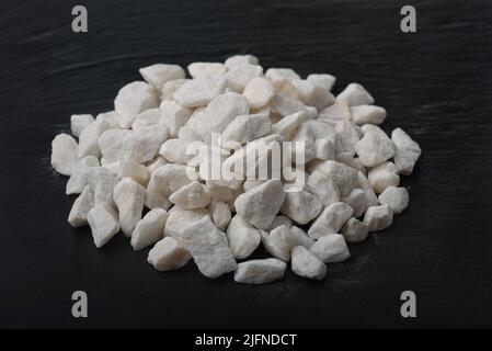Pile of natural crushed marble chips on black stone surface Stock Photo