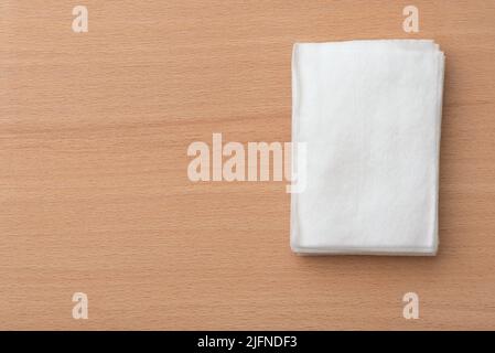 Top view of stacked unwrapped disposable wet wipes on wooden table with copy space Stock Photo