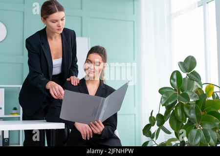 Young women leaders are checking financial statements from paper documents. Two female confident business worker dressed black suit in office checking Stock Photo