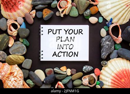 Put your plan into action symbol. Concept words Put your plan into action on beautiful black background. Sea stones and seashells. Busines planning an Stock Photo