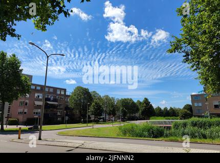 Rippled clouds named altocumulus undulatus over a neighbourhood in a Dutch town Stock Photo