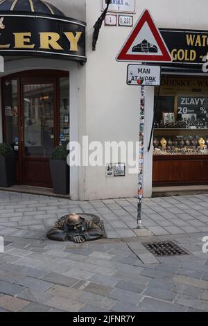 Bronze statue (1997) of sewer worker (Čumil, the watcher) emerging from a manhole in the center of Bratislava with its own warning sign 'Man at work'
