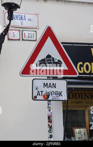 Warning sign next to bronze statue (1997) of sewer worker (Čumil, the watcher) emerging from a manhole in the center of Bratislava,see 2JFNR9D+2JFNR8E