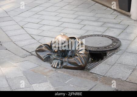 Quirky bronze statue (1997) of a sewer worker (Čumil, the watcher) emerging from a manhole in the center of Bratislava, Slovakia. Is he a peeping tom?