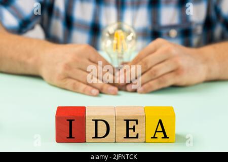 Colorful wooden blocks with the words Idea, Man holding a light bulb in his hand, Creative concept Stock Photo