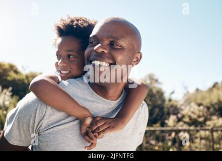 Closeup of a happy african american man bonding with his young little boy outside. Two black male father and son looking happy and positive while Stock Photo